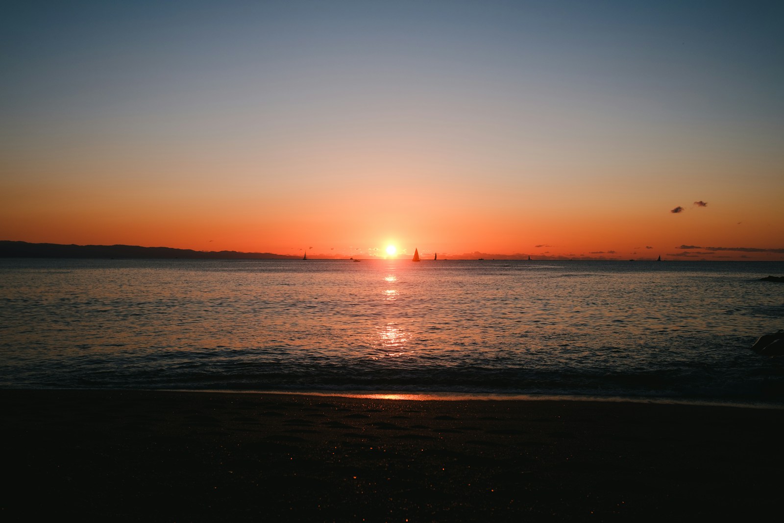 the sun is setting over the water at the beach